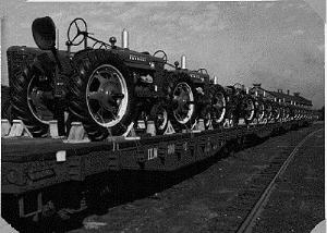 50s picture of brand new farmall tractors loaded on flat bed train cars